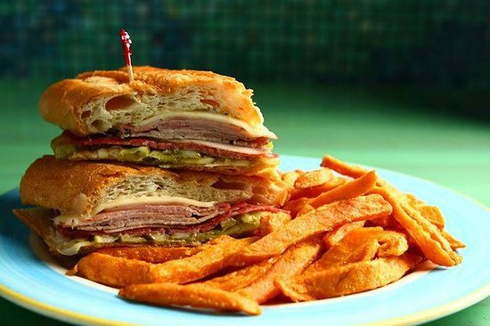 Sloppy Joe's on the Beach-min Sloppy Joe's on the Beach sandwich with layers of deli meats and pickles, served with sweet potato fries, highlighting the casual dining experience at the beachside restaurant in Treasure Island, FL.
